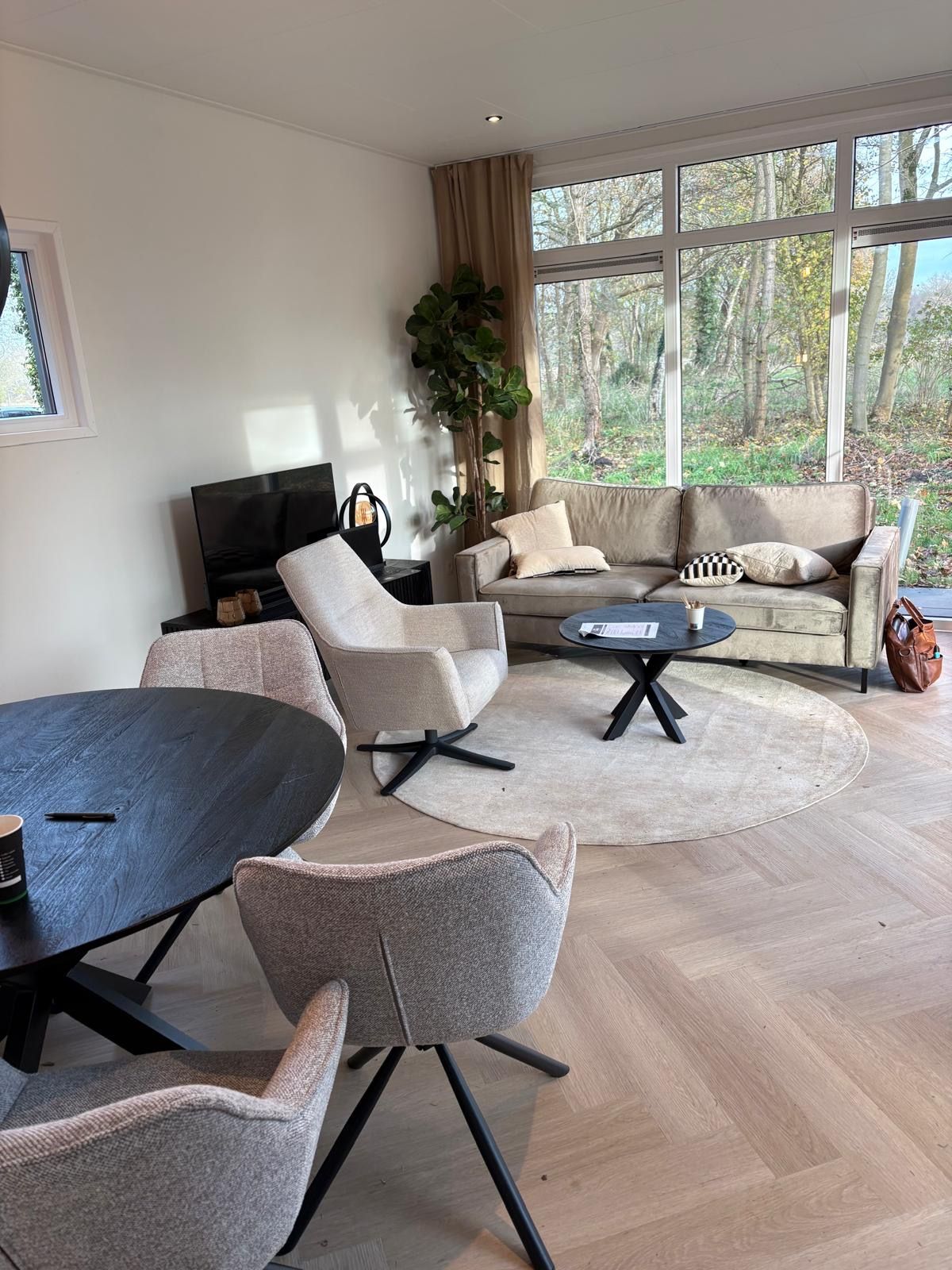 Lichte woonkamer met hout, grote ramen en zithoek